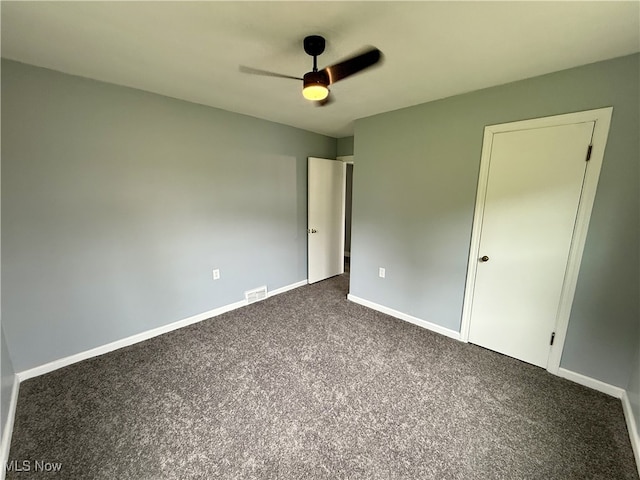 unfurnished bedroom featuring visible vents, ceiling fan, dark colored carpet, and baseboards