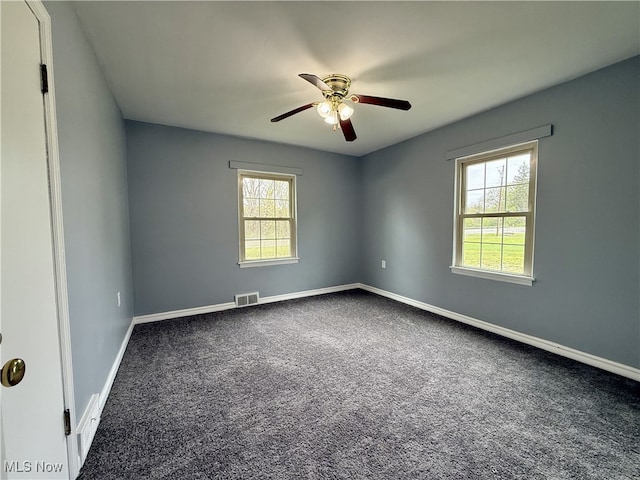 spare room with carpet flooring, a ceiling fan, visible vents, and baseboards