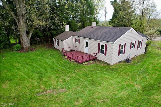 back of property with roof with shingles, a chimney, a yard, and a wooden deck