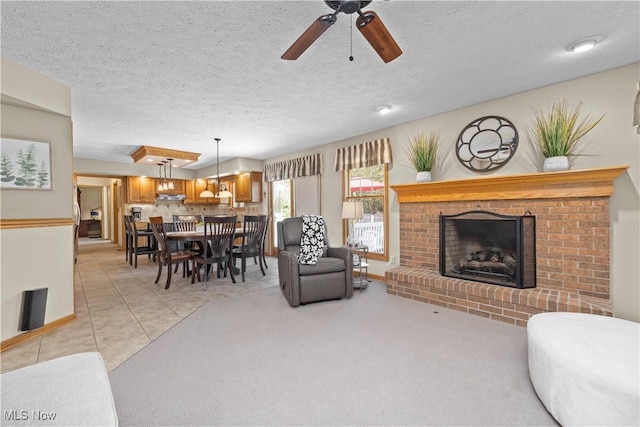 living room with light tile patterned floors, a ceiling fan, a textured ceiling, and a brick fireplace