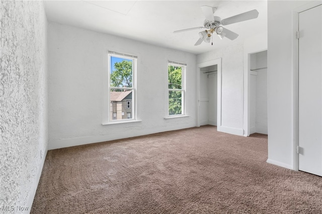 unfurnished bedroom with ceiling fan, multiple closets, and carpet floors