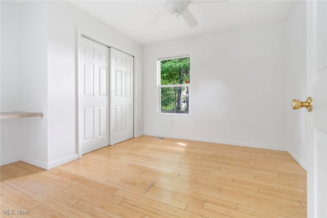 unfurnished bedroom with a closet, a ceiling fan, hardwood / wood-style flooring, and baseboards