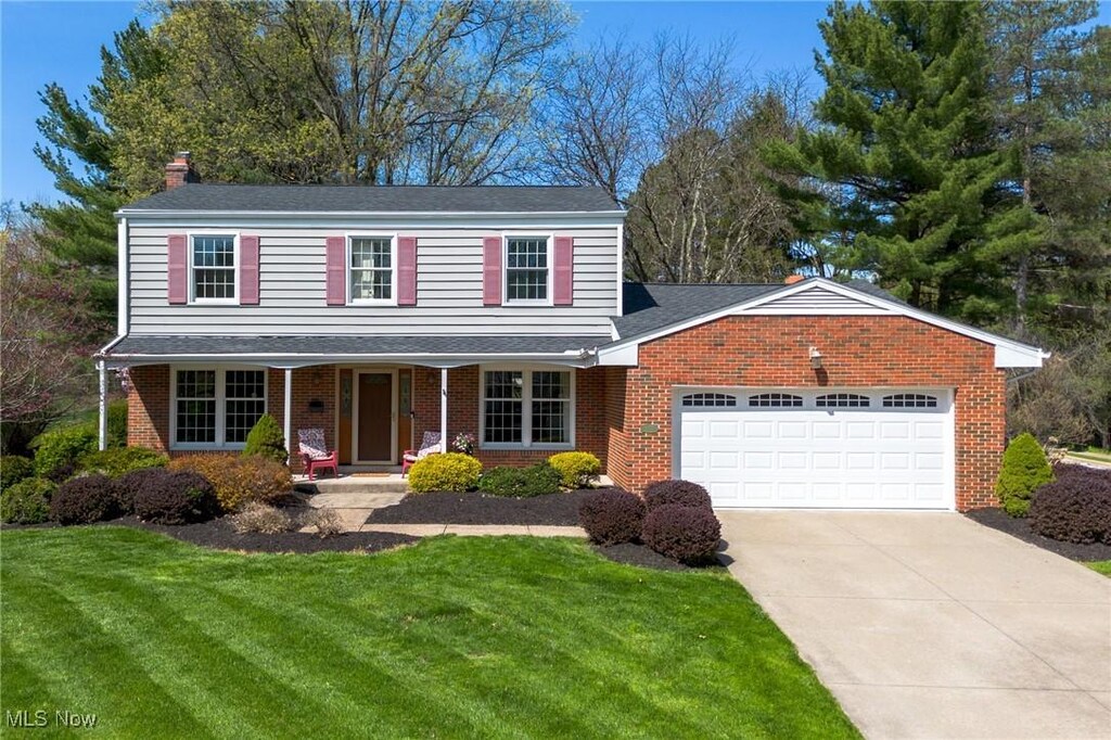 traditional-style home with a chimney, a front lawn, concrete driveway, and an attached garage
