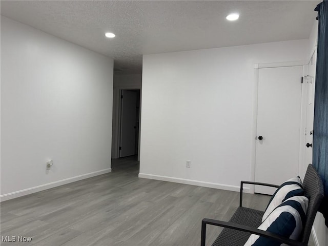 living area with baseboards, recessed lighting, a textured ceiling, and wood finished floors
