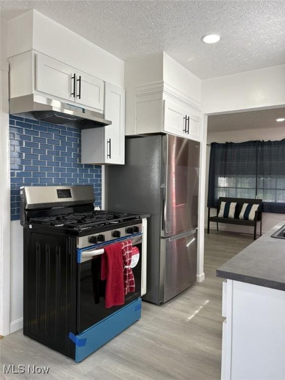 kitchen with backsplash, dark countertops, white cabinets, stainless steel appliances, and light wood-style flooring