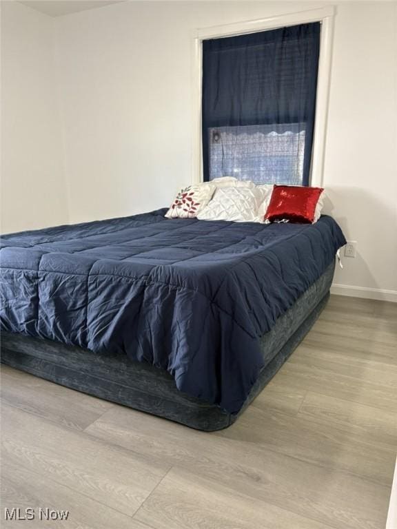 bedroom with baseboards and wood finished floors