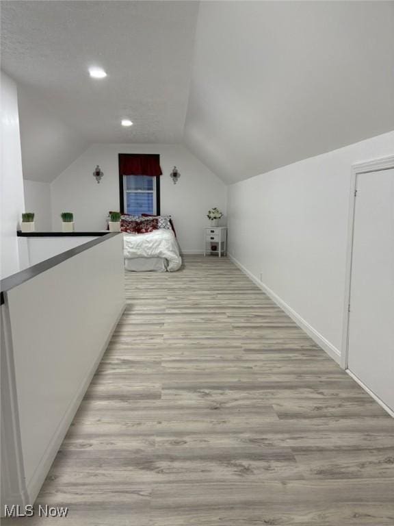 bonus room with baseboards, vaulted ceiling, recessed lighting, and light wood-style flooring
