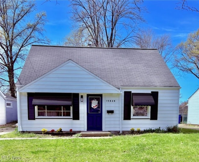 bungalow-style home featuring roof with shingles and a front yard