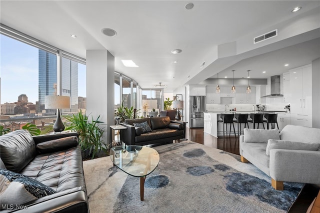living room with dark wood-style flooring, visible vents, recessed lighting, and a city view