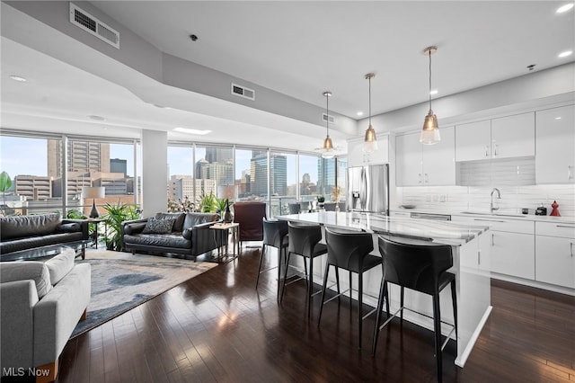 kitchen featuring a view of city, visible vents, dark wood-type flooring, open floor plan, and stainless steel refrigerator with ice dispenser