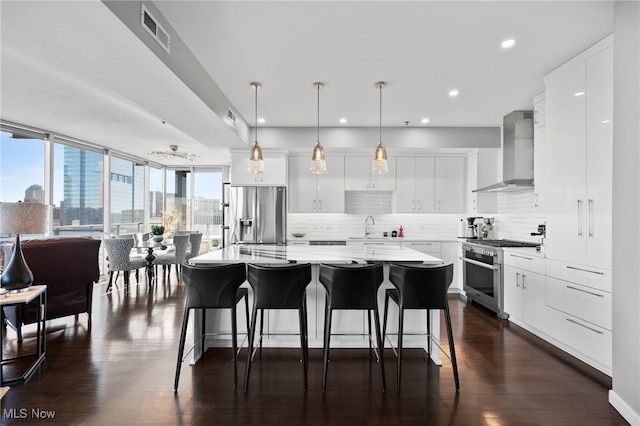 kitchen featuring appliances with stainless steel finishes, backsplash, a center island, visible vents, and wall chimney exhaust hood