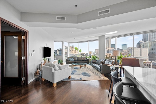 living area with dark wood-type flooring, visible vents, recessed lighting, and baseboards