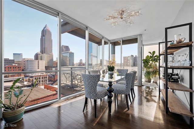 sunroom / solarium featuring wood finished floors, a wall of windows, and a city view
