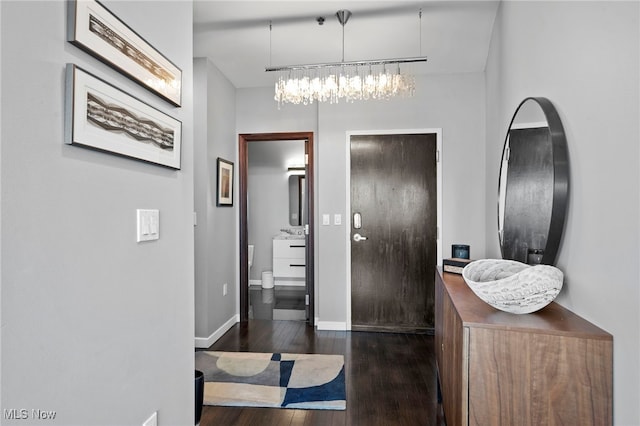 foyer with an inviting chandelier, hardwood / wood-style floors, and baseboards