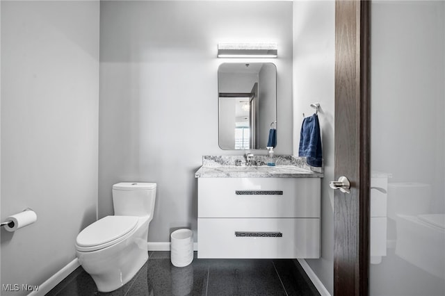 bathroom with vanity, toilet, and baseboards