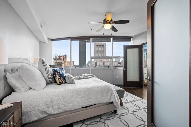 bedroom with wood finished floors, a city view, and multiple windows