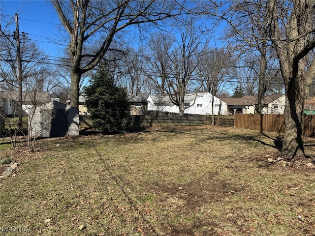 view of yard with fence, a shed, a residential view, and an outbuilding