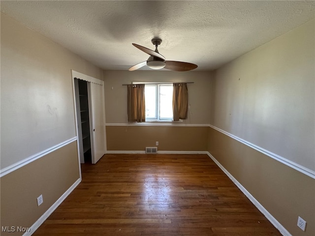 unfurnished bedroom featuring wood finished floors, visible vents, a closet, and a textured ceiling