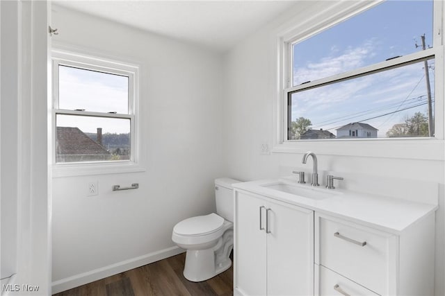 half bathroom featuring wood finished floors, toilet, vanity, and baseboards