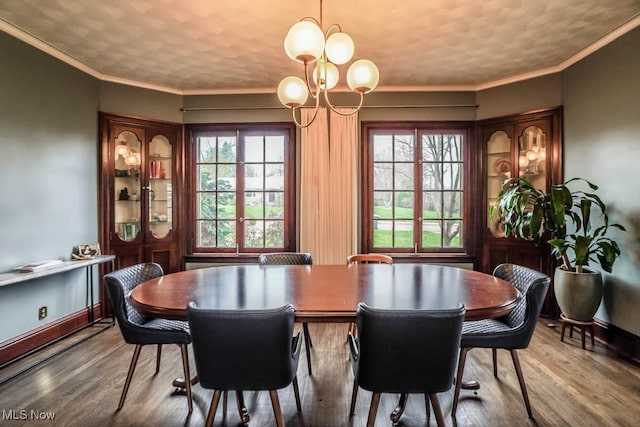 dining room featuring ornamental molding, a notable chandelier, wood finished floors, and baseboards