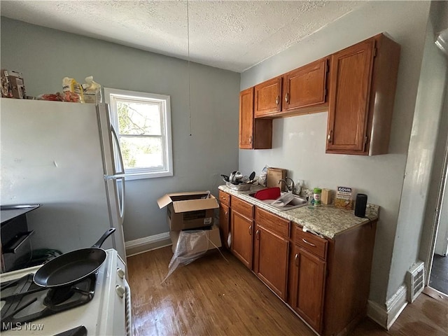 693 E 130th St, Cleveland, OH 44108 - kitchen with a sink, brown cabinets, white appliances, light countertops, and wood finished floors