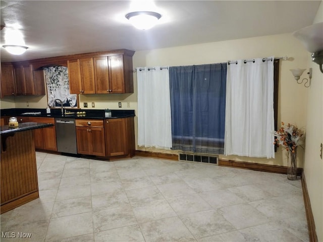 kitchen with dark countertops, visible vents, brown cabinets, and dishwasher