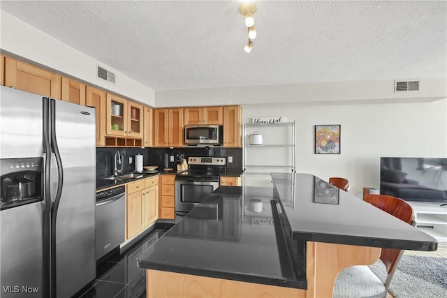 kitchen with a textured ceiling, a sink, stainless steel appliances, and visible vents