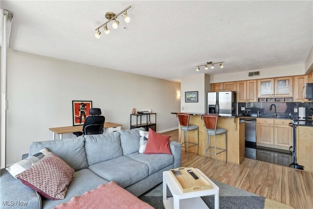 living area with track lighting, visible vents, baseboards, and dark wood finished floors