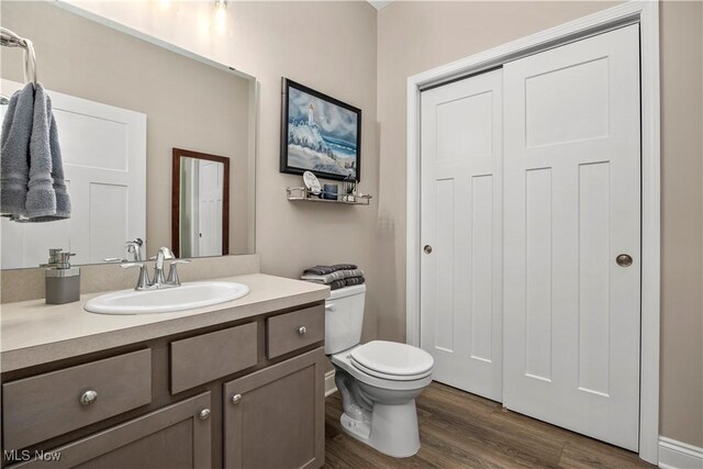 bathroom with wood finished floors, toilet, and vanity