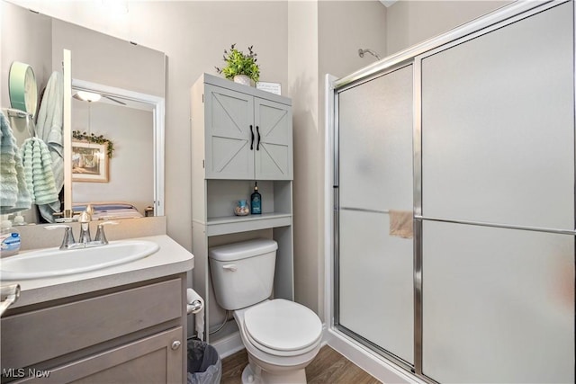 bathroom featuring toilet, wood finished floors, a shower stall, and vanity
