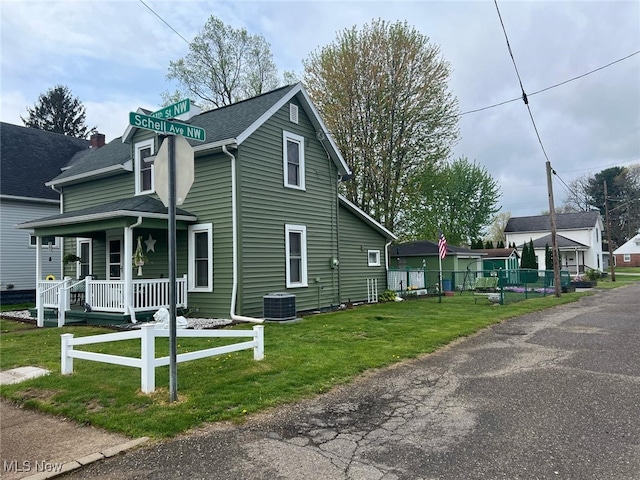 view of home's exterior featuring covered porch, fence, a yard, and central AC