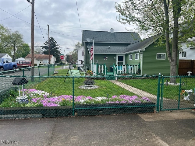 view of front of house featuring a front lawn, a chimney, fence private yard, and roof with shingles