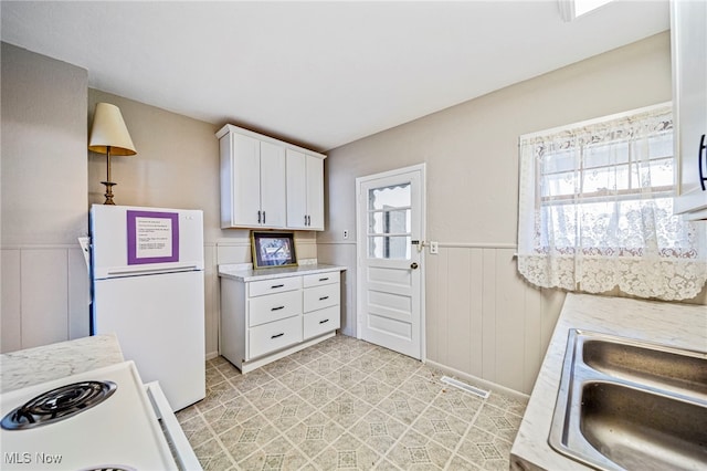 1420 Bridge St, Ashtabula, OH 44004 - kitchen with wainscoting, a sink, light countertops, and freestanding refrigerator