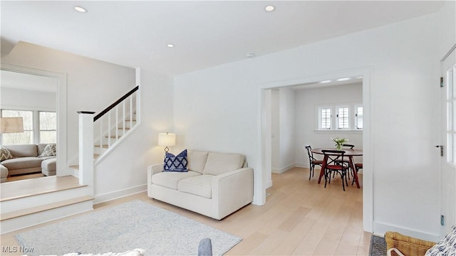 living area with baseboards, recessed lighting, stairway, and light wood-style floors