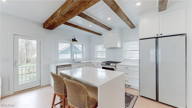 kitchen featuring gas stove, light countertops, a sink, white cabinetry, and white fridge