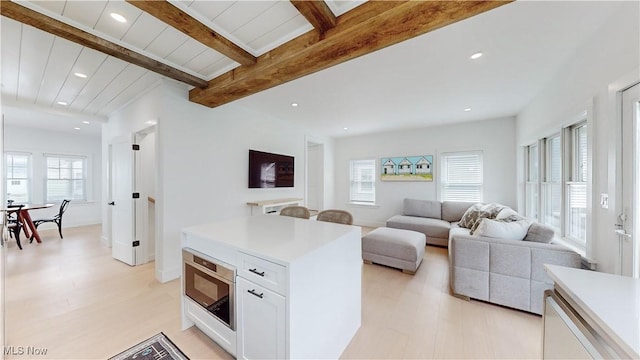 kitchen with recessed lighting, light countertops, white cabinets, beam ceiling, and built in microwave