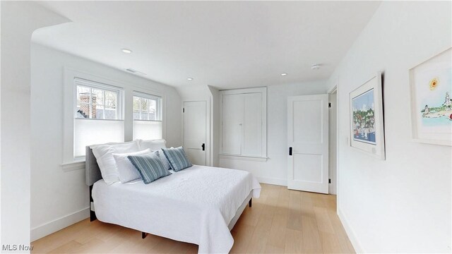 bedroom with baseboards, light wood-type flooring, visible vents, and recessed lighting