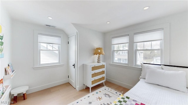 bedroom with light wood finished floors, visible vents, multiple windows, and baseboards