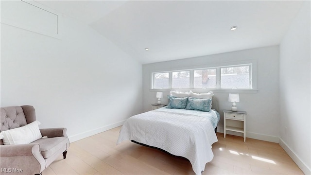 bedroom featuring attic access, light wood-style floors, lofted ceiling, and baseboards