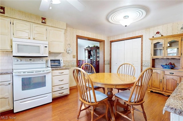 dining room with a toaster, light wood finished floors, a ceiling fan, and wallpapered walls