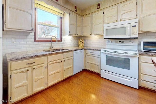 kitchen featuring tasteful backsplash, white appliances, a toaster, a sink, and light wood-type flooring