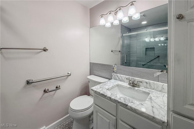 full bathroom featuring vanity, tile patterned floors, toilet, a stall shower, and baseboards