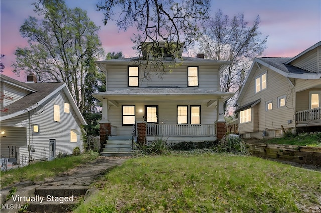 traditional style home with a porch, a front yard, and a chimney