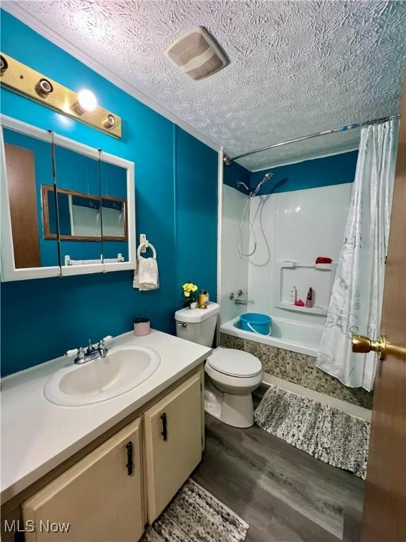 full bathroom with vanity, shower / tub combo, toilet, a textured ceiling, and wood finished floors