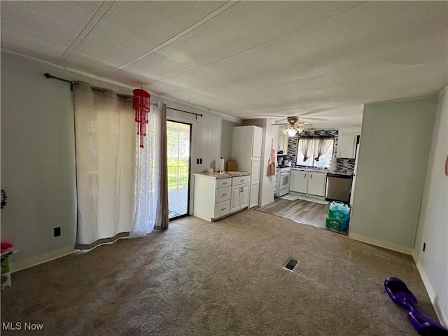interior space featuring carpet flooring, a ceiling fan, visible vents, and a wealth of natural light