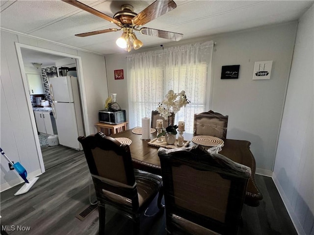 dining space with dark wood-type flooring, a ceiling fan, and baseboards