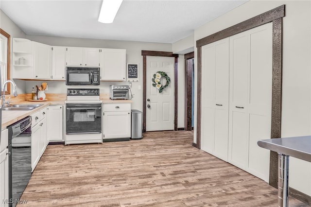 39233 Jones Rd, Litchfield, OH 44253 - kitchen with black appliances, a sink, white cabinets, and light wood-style floors