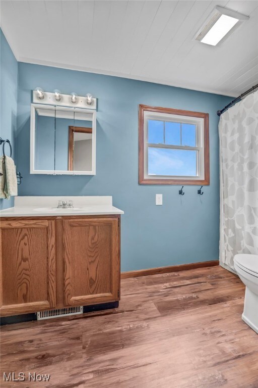 39233 Jones Rd, Litchfield, OH 44253 - full bath featuring vanity, toilet, visible vents, baseboards, and wood finished floors