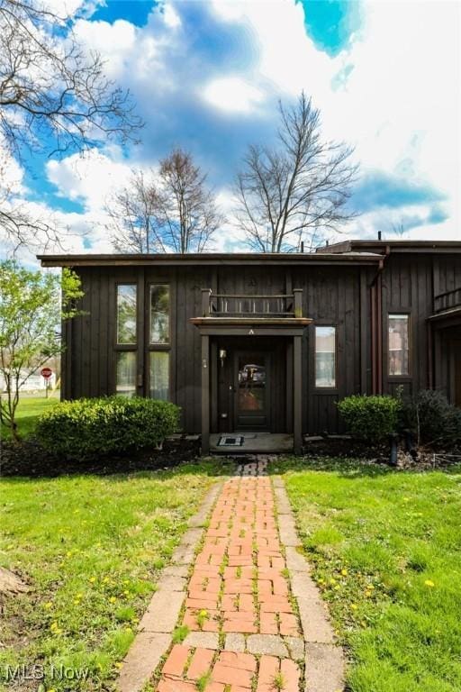 view of exterior entry featuring board and batten siding and a yard