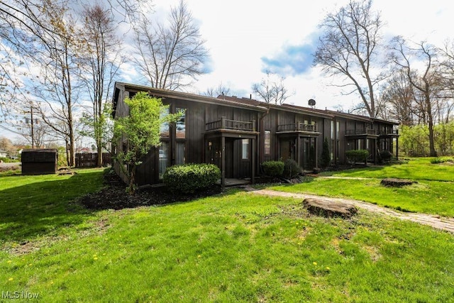 rear view of house with a yard and a balcony